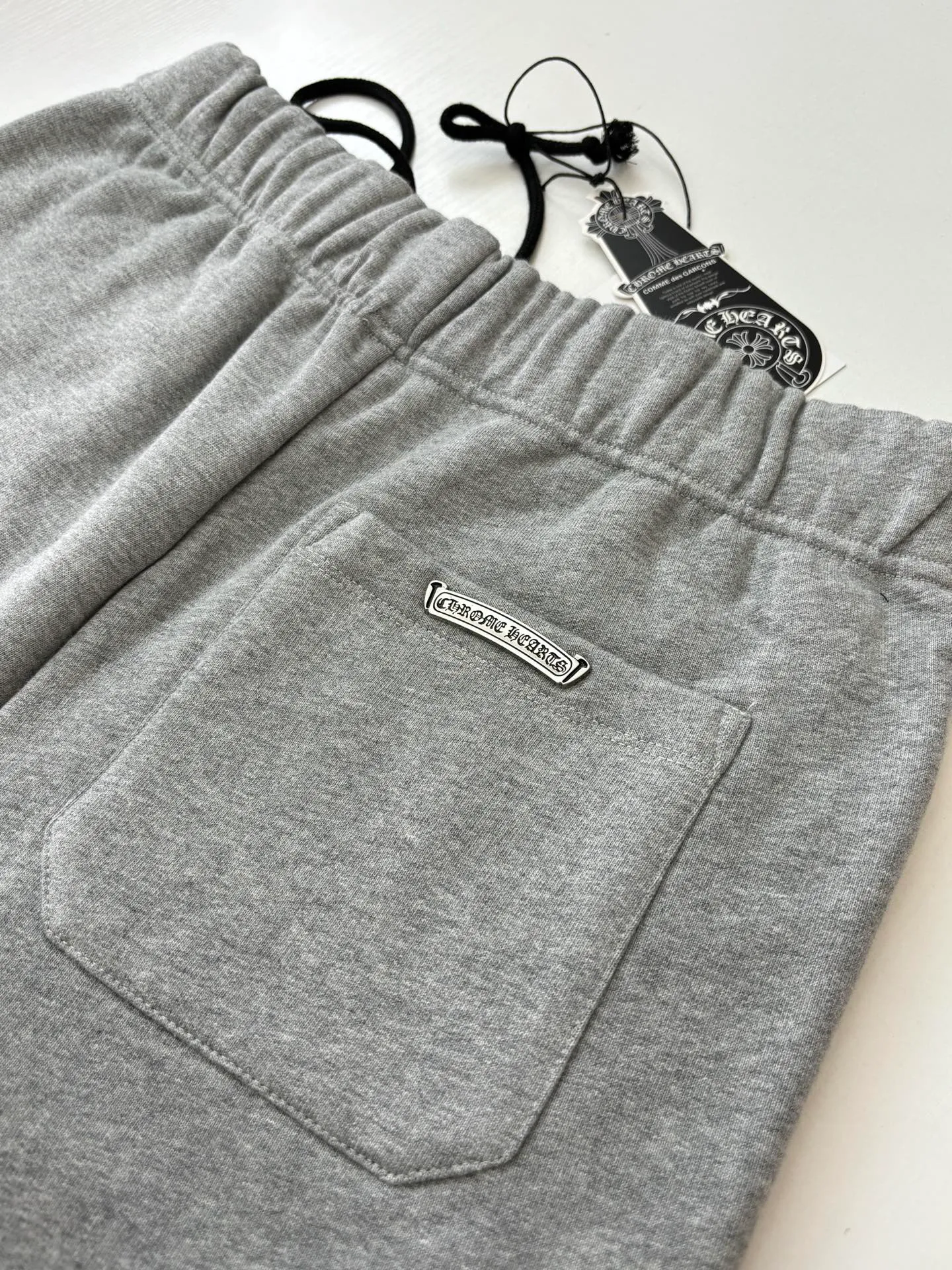 P346 Chrome Hearts*/Chrome Hearts 26SS early spring new patch embroidered shorts The fabric is made of a blended ratio of 80% cotton and 20% polyester. It is woven with a siro spinning process of 32-count base yarn and 10-count veil to form a high-weight terry cloth base of 380g/㎡. The cotton-polyester blended material combines the skin-friendly breathability of cotton and the anti-wrinkle shape retention of polyester. The high-weight fabric gives the trousers excellent stiffness and drape. The core technology is patch embroidery, which is completed with the help of TAJIMA computer embroidery machine. The black special-shaped patch is precisely sewn to the trouser fabric through lock stitches. The embroidery stitch density is even and the edges are neatly hemmed, forming a three-dimensional relief-like visual effect. Size: S/M/L/XL